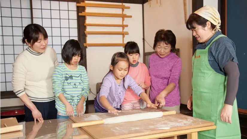 子どもたちが大人に教わりながらそば打ちを行う様子